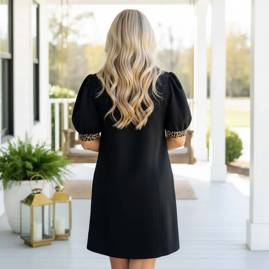 Woman wearing the BOLD MOVES DRESS, showcasing a black design with leopard trim and a sleek silhouette.