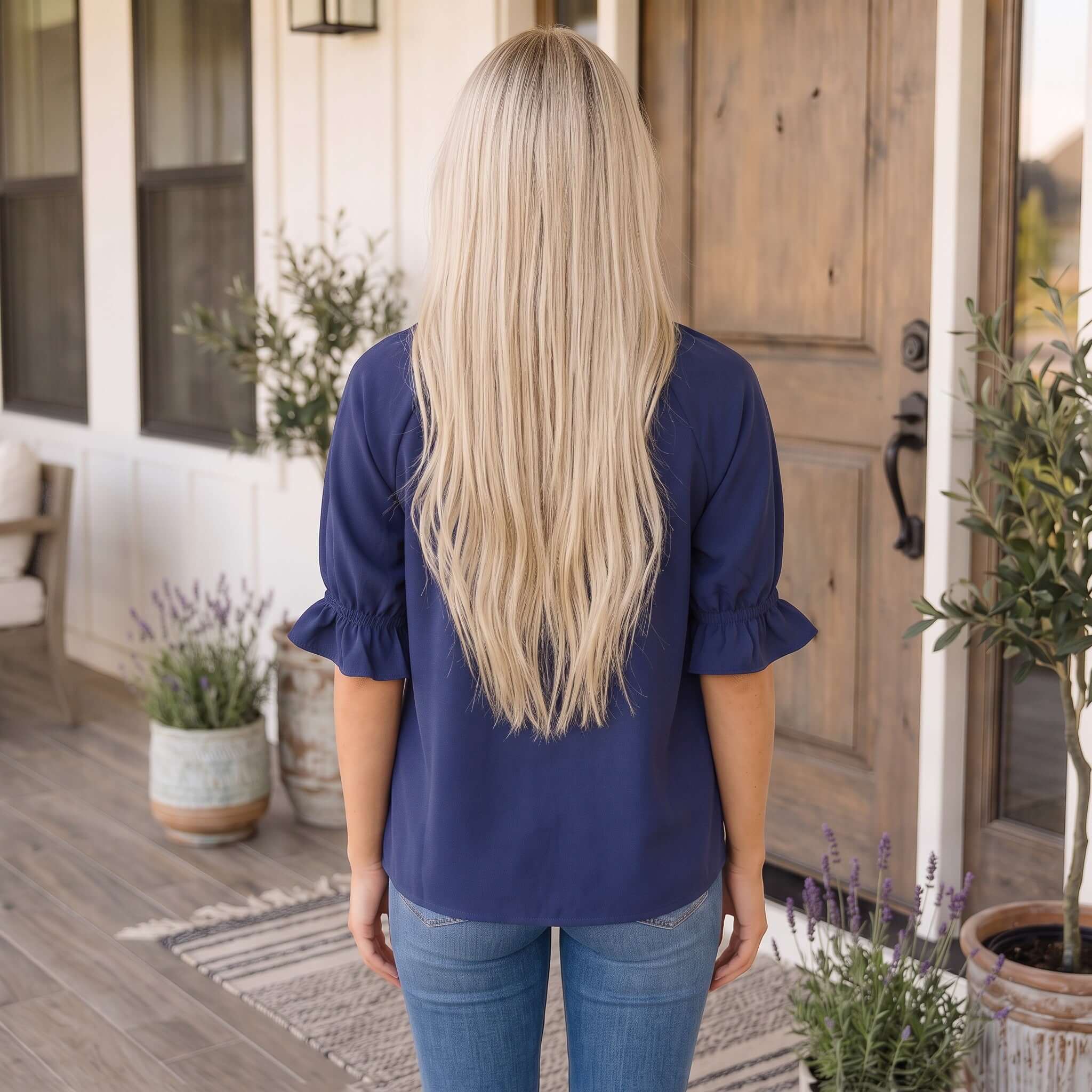 Woman wearing a BREAKFAST AT MIDNIGHT TOP in Midnight Blue, showing delicate scalloped trim and stylish back view.