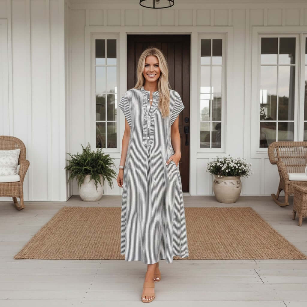 Model wearing RIGHT DIRECTION DRESS, a striped maxi dress with half button front, standing on a porch.