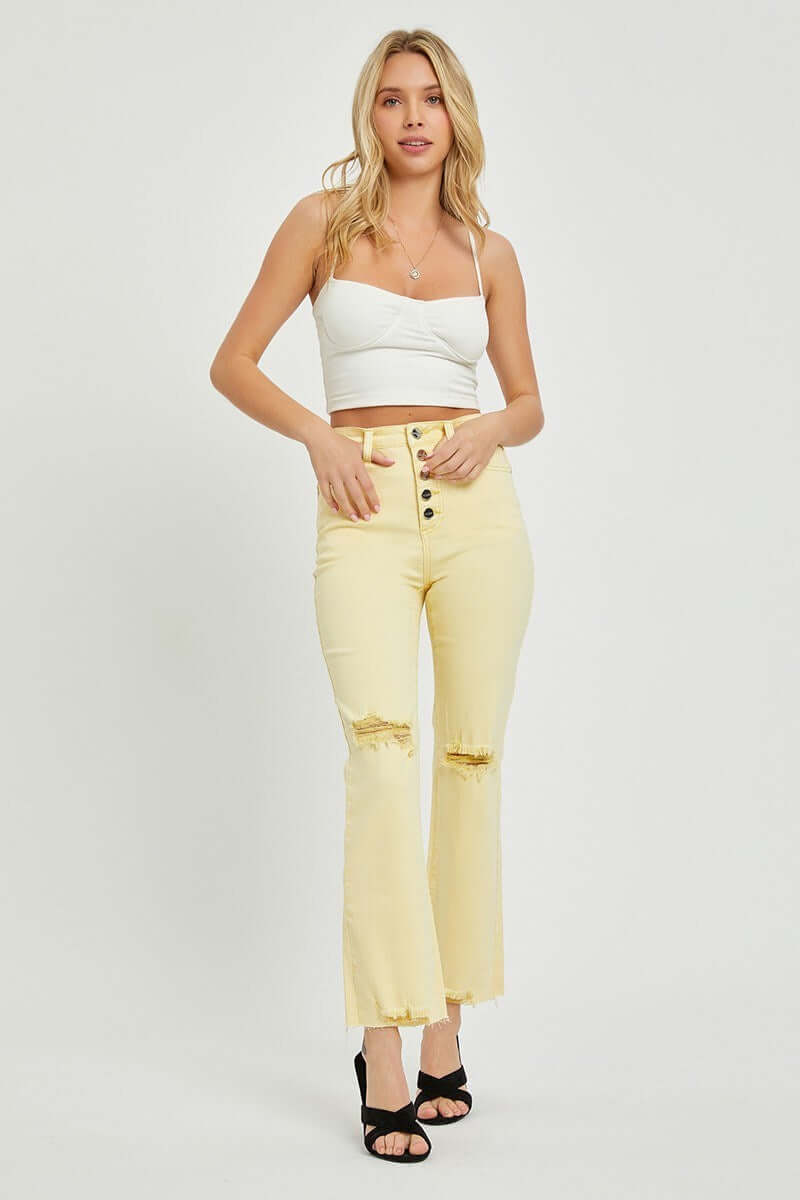 Young woman modeling Risen Sunny Girl high rise pale yellow jeans with distressed details.