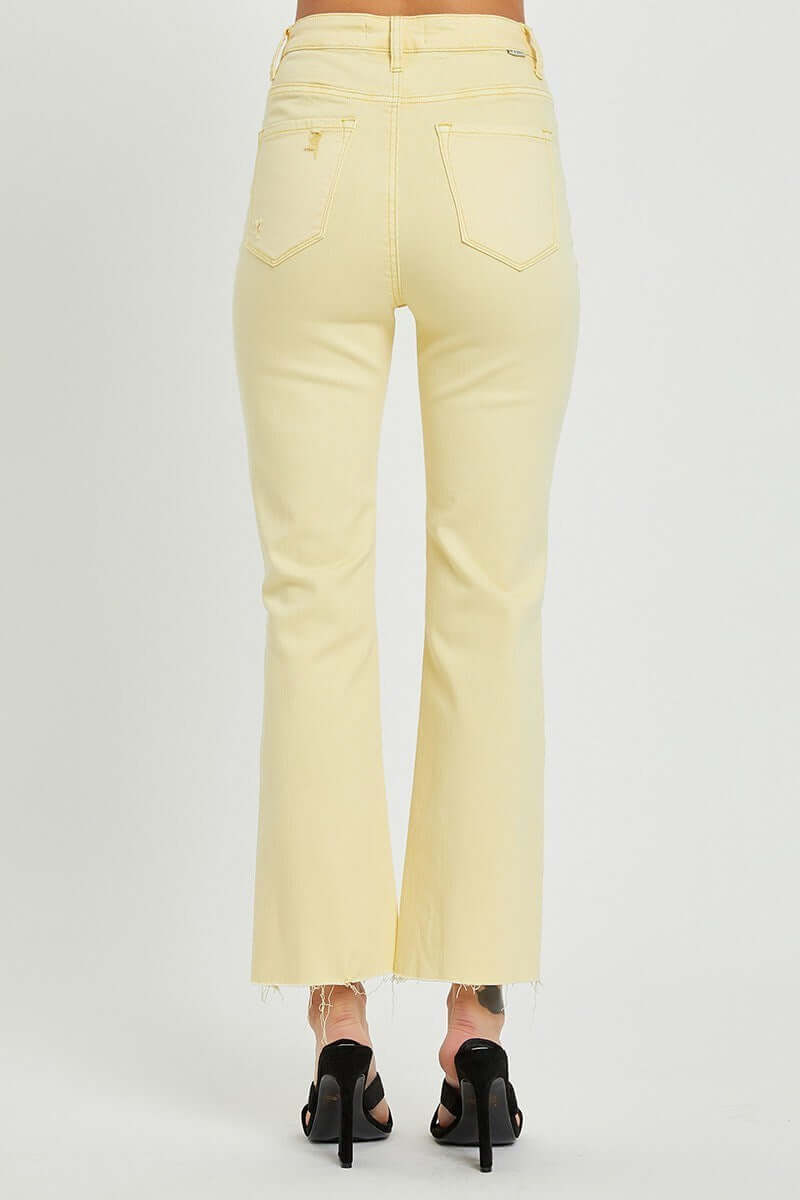 Back view of Risen Sunny Girl Denim, high-rise pale yellow jeans with distressed hems and button fly.
