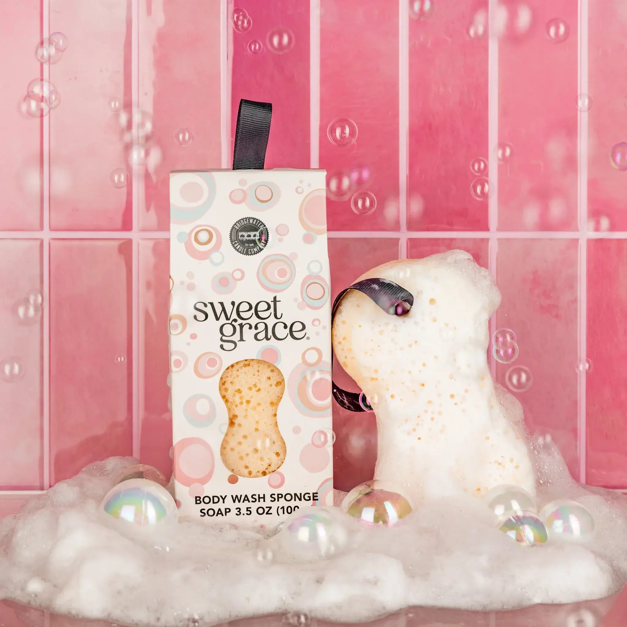 SWEET GRACE BATH SPONGE in bubbly water with packaging, perfect for cleansing and indulging in Sweet Grace fragrance.