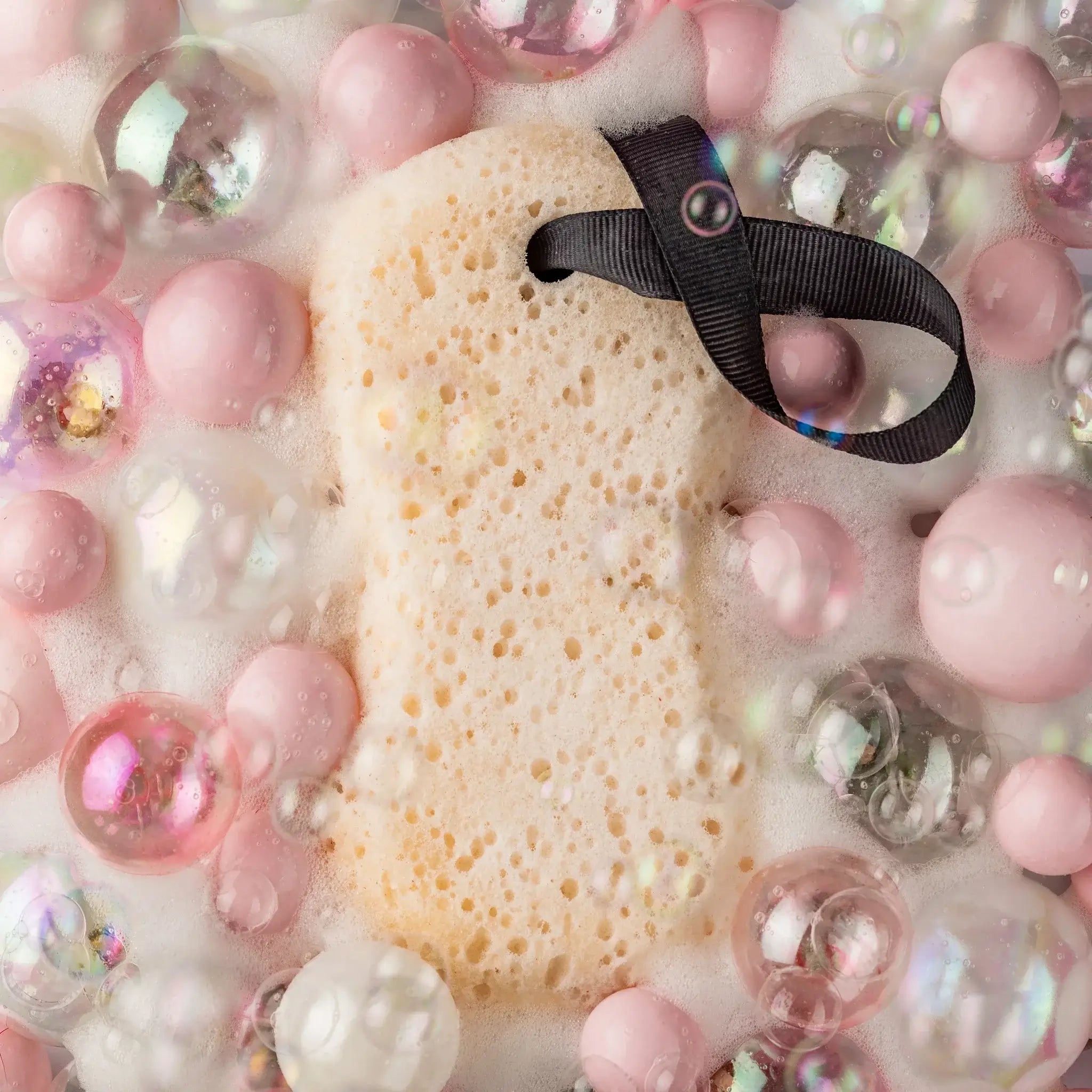 SWEET GRACE BATH SPONGE surrounded by colorful bubbles and foam for a luxurious shower experience.
