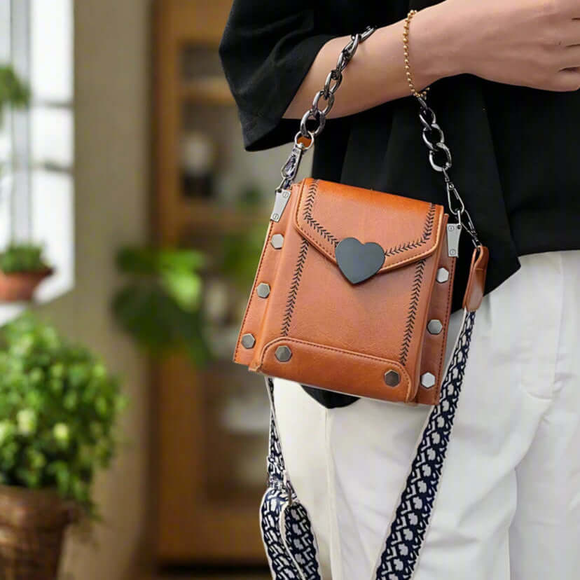 Urban Sweetheart Crossbody Bag in rich maple brown with heart closure and chain details.