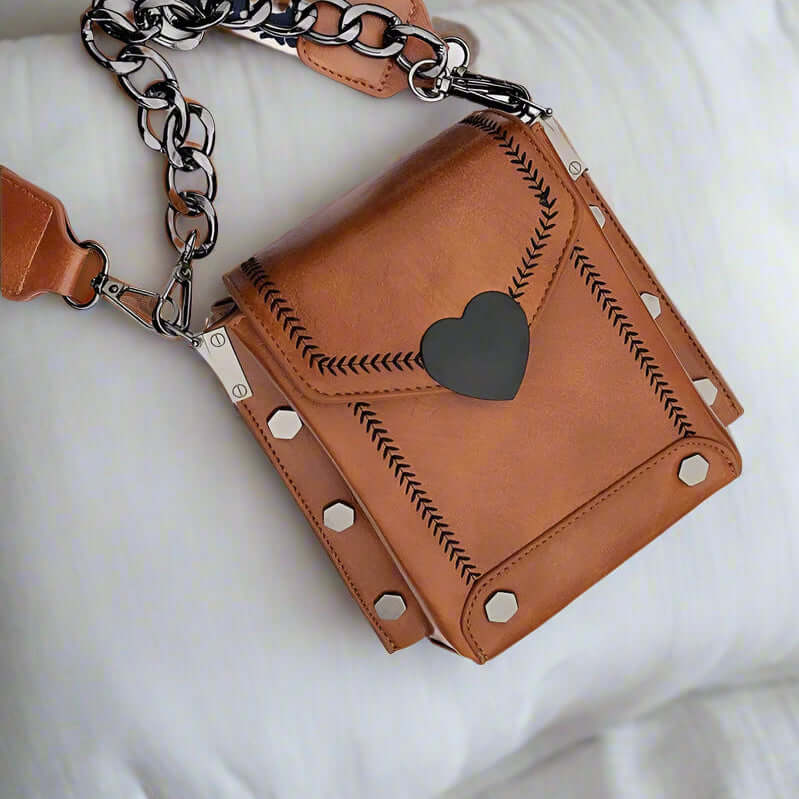 Urban Sweetheart crossbody bag in maple brown faux leather with heart closure and studded details, ideal for everyday wear.