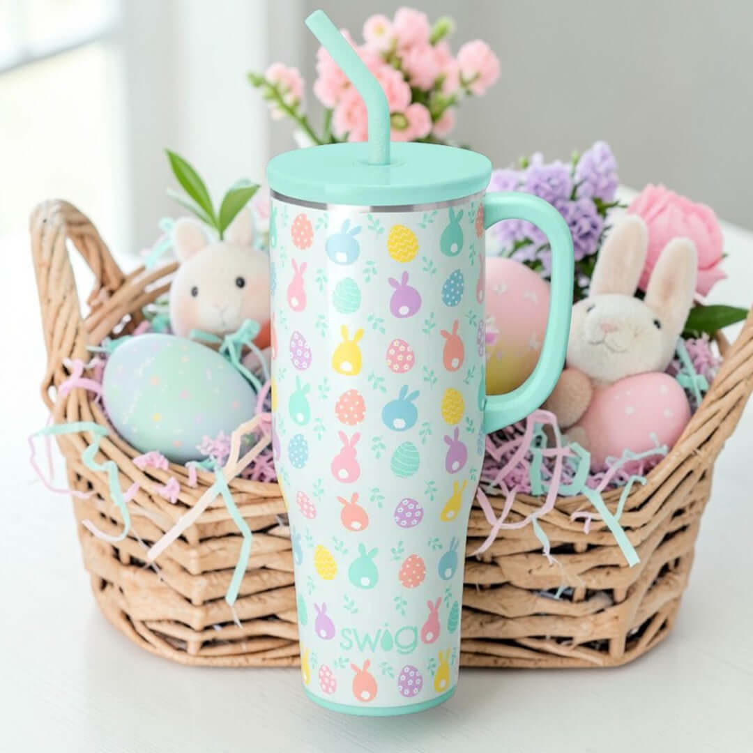 EGG HUNT 40 OZ MEGA MUG - Swig Life next to a festive Easter basket filled with bunnies and colorful eggs.
