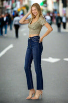 Model wearing midrise ADELINE Jeans by Risen in dark wash, styled with a chic crop top on a city street.