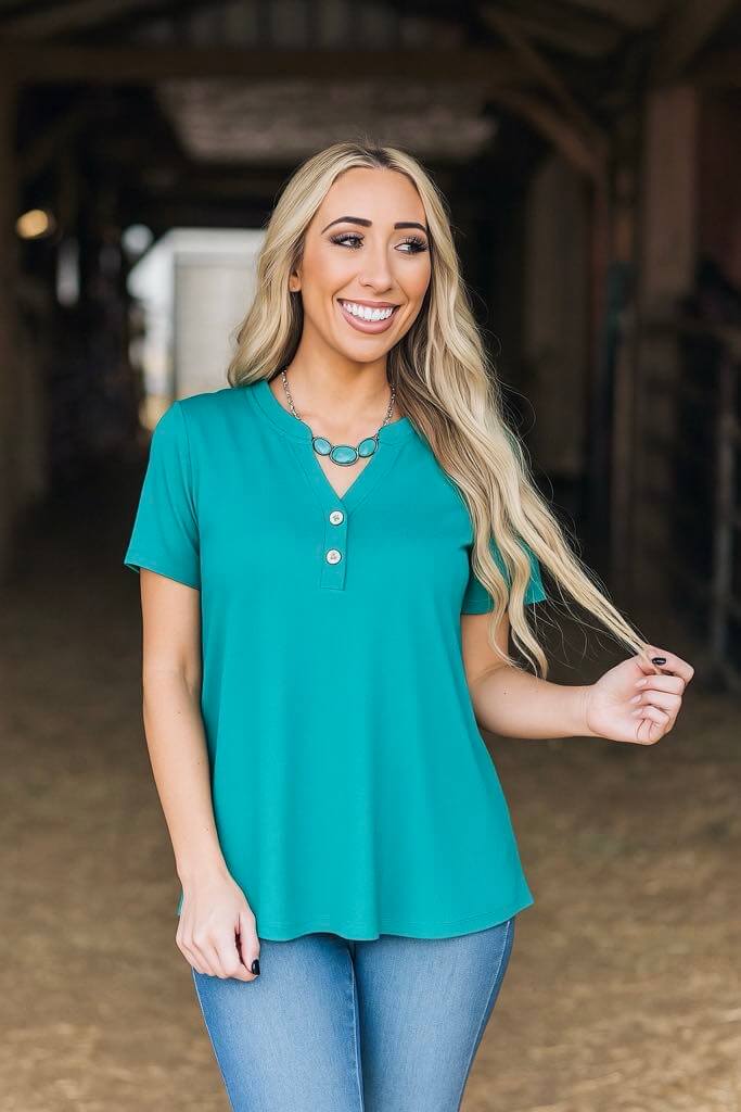 Woman in aqua Everyday Energy Top by Andrée, smiling and posing in a relaxed fit, ideal for casual wear.