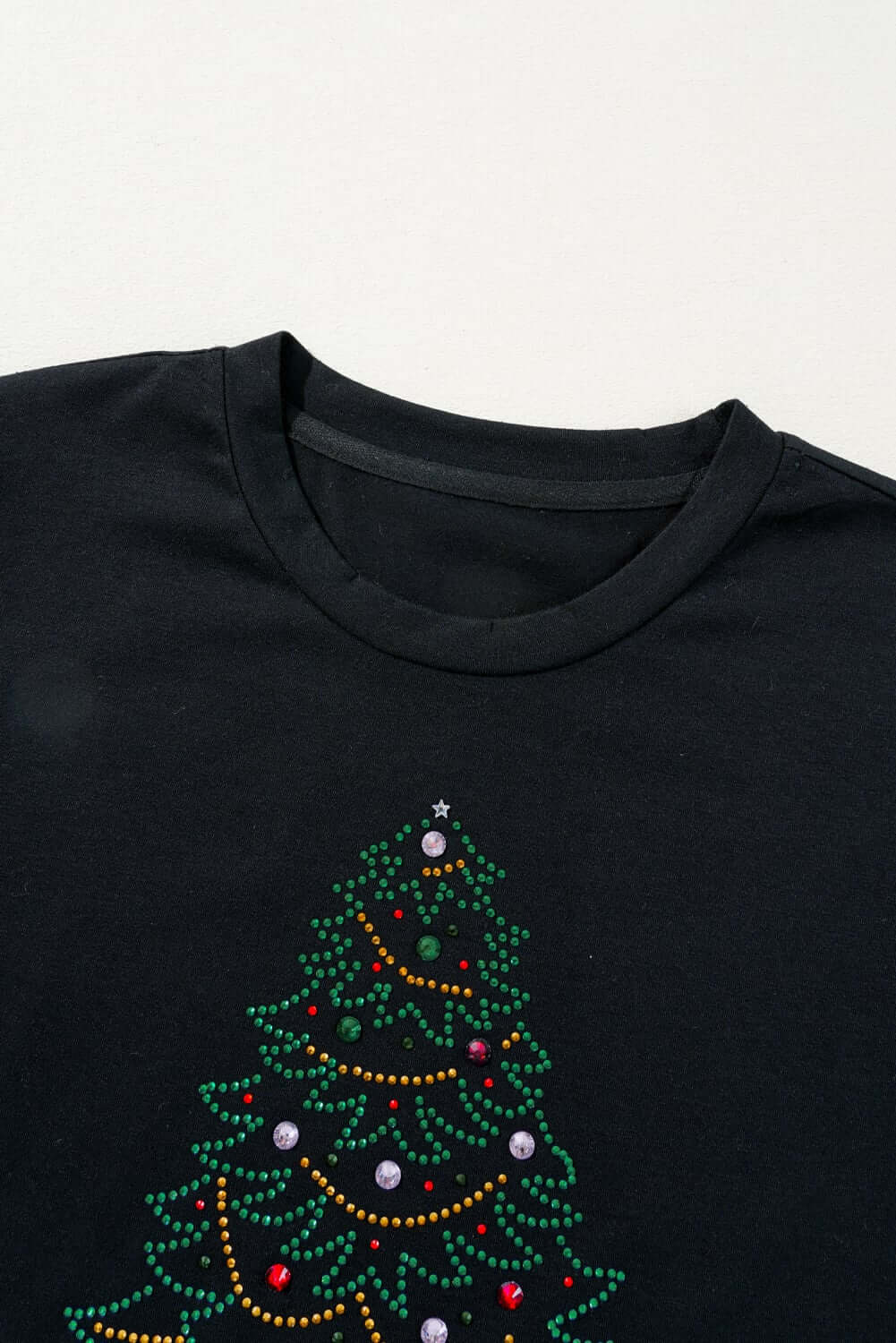 Black t-shirt featuring a colorful studded Christmas tree design, perfect for festive casual wear.
