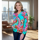 Model wearing LAGUNA LUXE BLOUSE - JODIFL in vibrant teal and pink, showcasing a stylish look against a city backdrop.