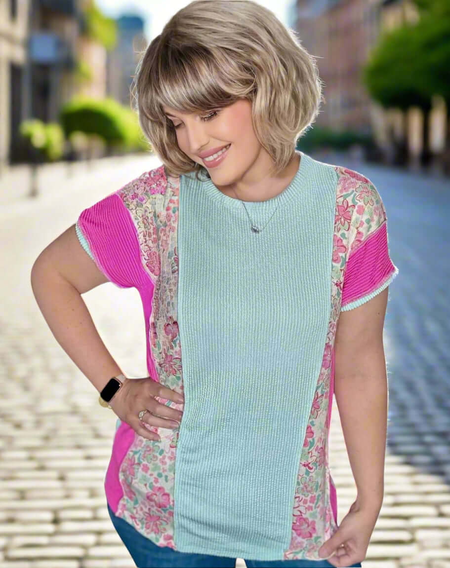 Model wearing a mint and floral patch top, featuring short sleeves and ribbed texture, set against an outdoor city background.