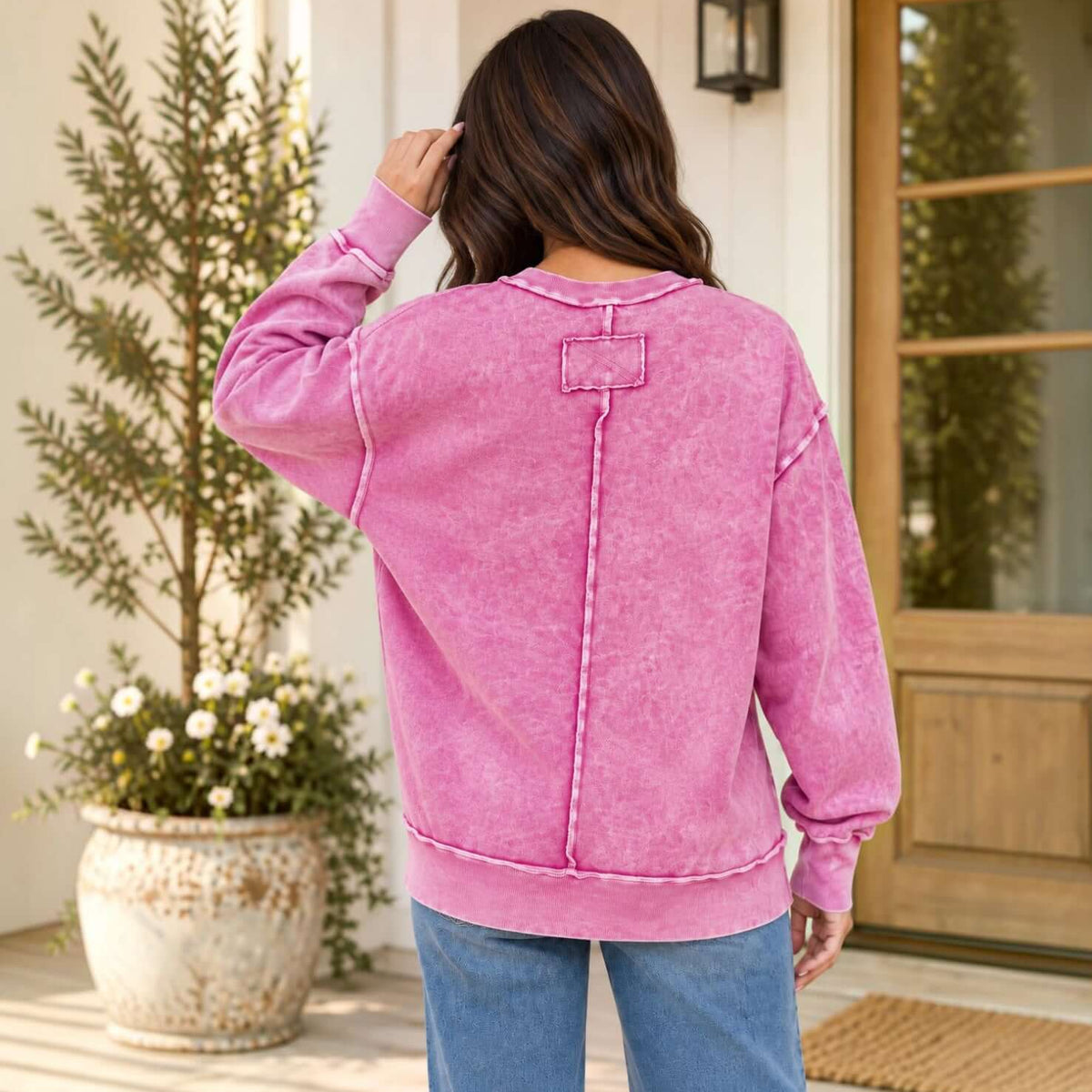 Back view of a woman wearing the WEEKEND COZY PULLOVER (3 colors) in pink, showcasing exposed seams and relaxed style.