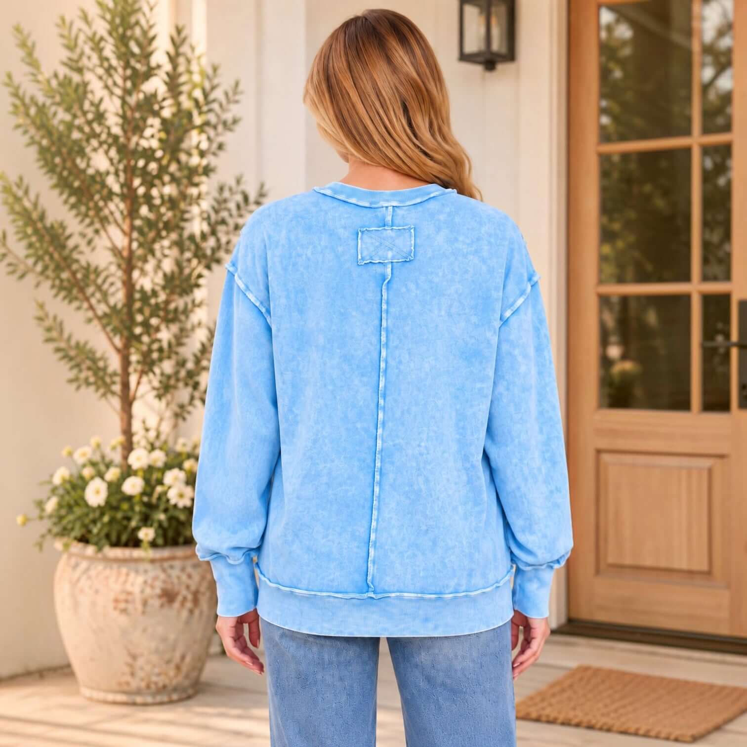Back view of a woman wearing the WEEKEND COZY PULLOVER (3 colors) in light blue, showcasing its relaxed style.