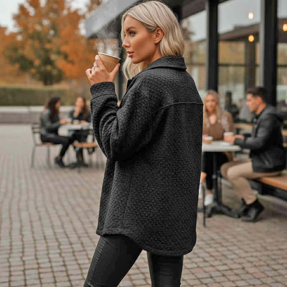 Woman wearing WARM IMPRESSIONS BUTTON DOWN shacket, sipping coffee outdoors at a cafe.