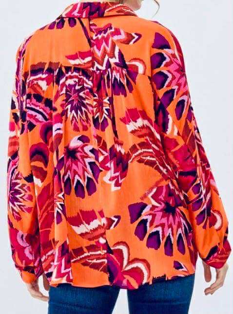 Back view of the LAVA LUXE BLOUSE - JODIFL showcasing vibrant orange and pink floral patterns.