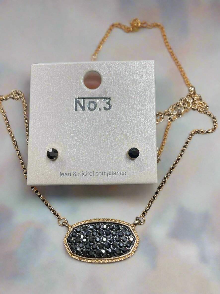 Druzy oval pendant necklace and matching stud earrings in black on stylish display.