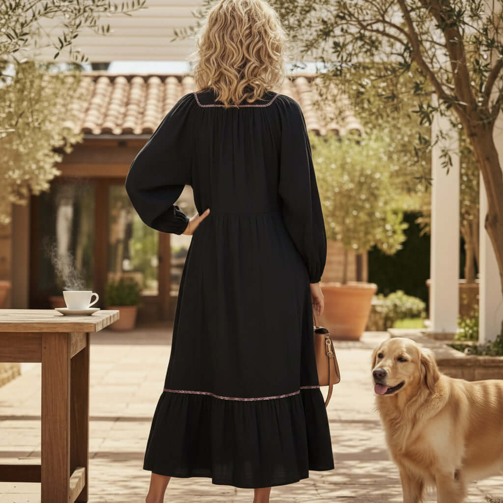 Back view of a woman in a GRACEFUL INSTINCTS MAXI DRESS with balloon sleeves, standing next to a golden retriever.