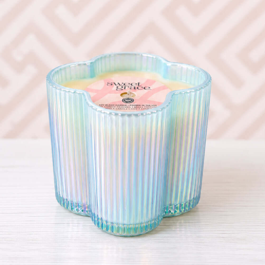 Sweet Grace Beauty Blooms Candle in iridescent blue flower-shaped glass vessel on a light background.