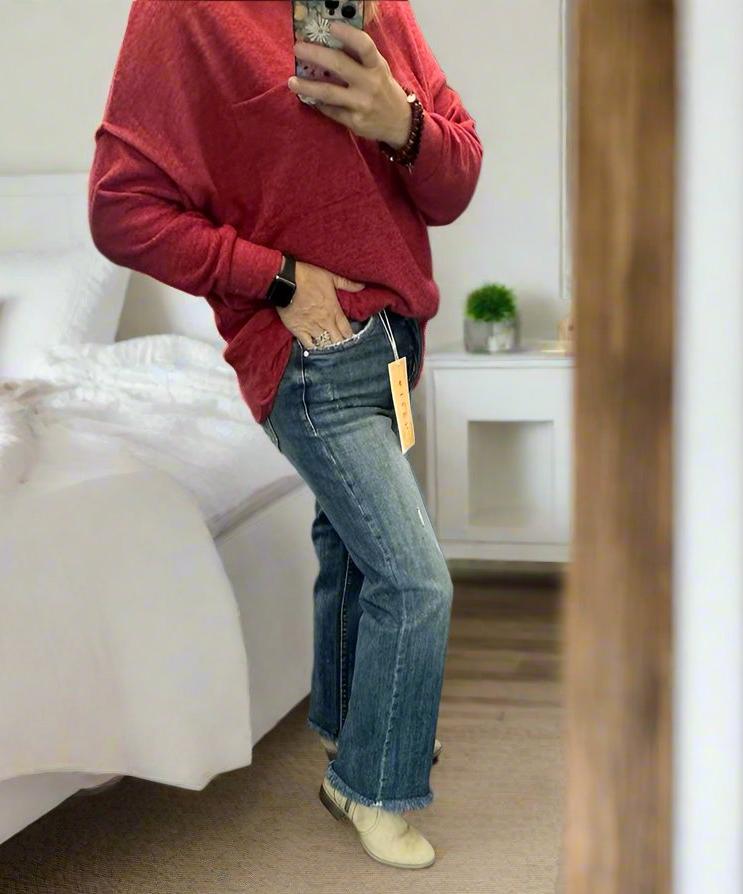Model showcasing RISEN Bianca Jeans with frayed hem, styled with a cozy red top and neutral shoes.