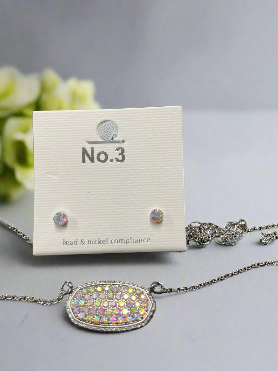 Druzy oval pendant necklace with matching stud earrings in rainbow colors, displayed on packaging.