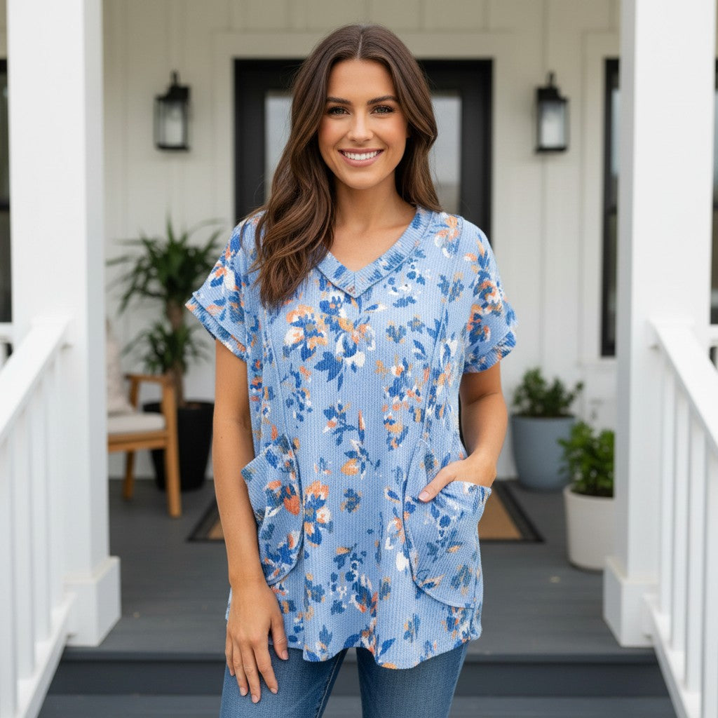 HELLO YOU TOP (blue) featuring a stylish floral design, short sleeves, and convenient front pockets.