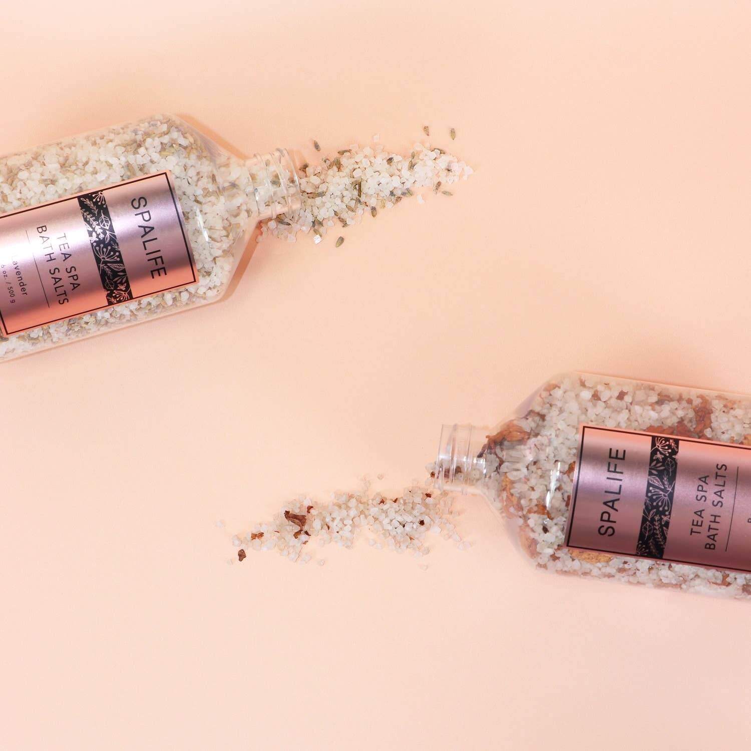SpaLife Petal-Infused Bath Salts (2 SCENTS) in elegant bottles spilling on a soft pink background.