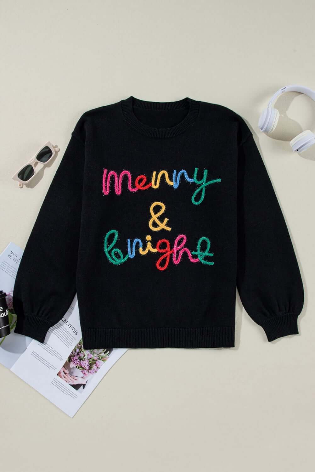 Merry & Bright sweater by Vivian-Lu with colorful tinsel lettering on a black background, perfect for holiday celebrations.