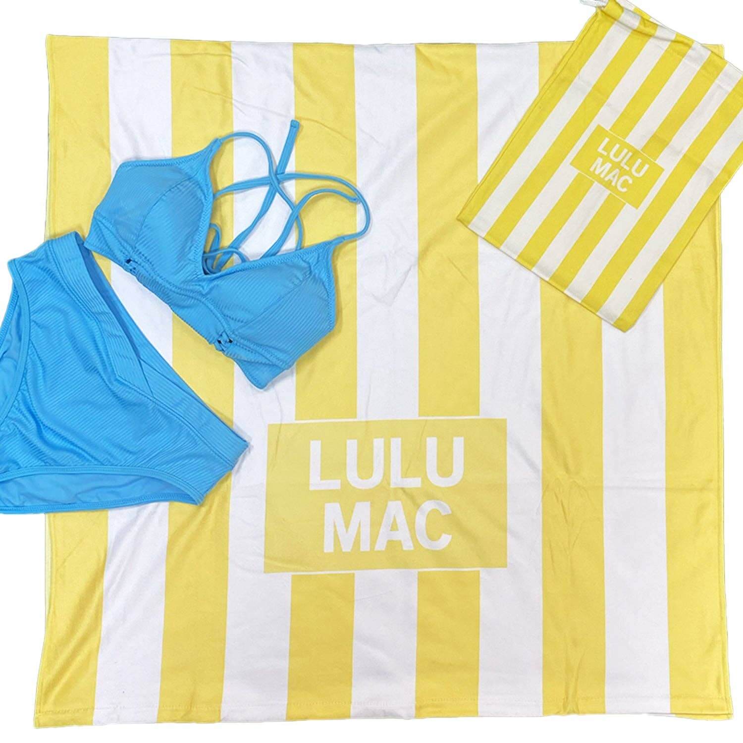 LULU MAC DARBY BEACH TOWEL (yellow) with blue bikini and burlap carrying case on striped background.