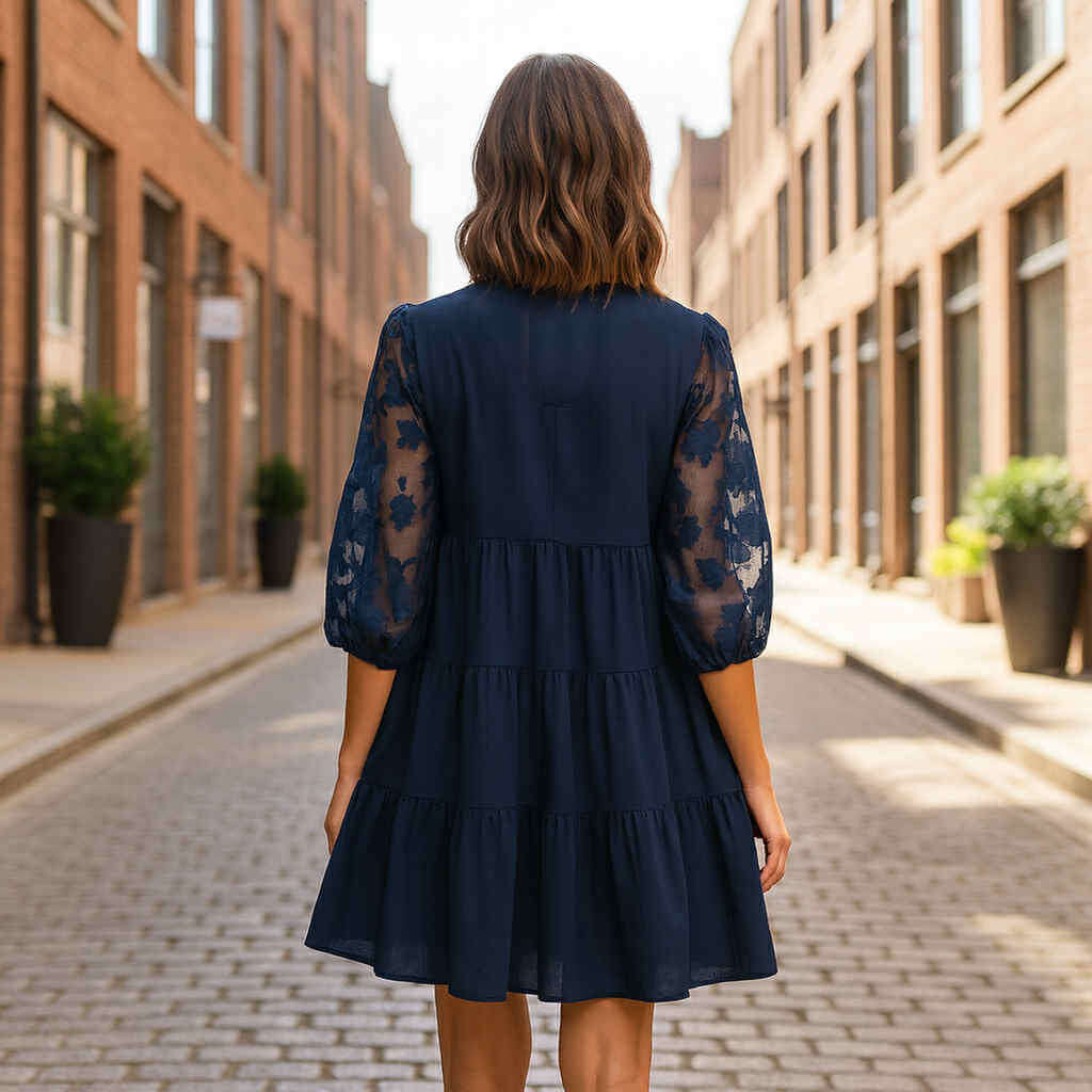 Woman wearing DEEP SEA DREAMS DRESS Umgee, showcasing the navy tiered design and floral sleeves in an urban setting.