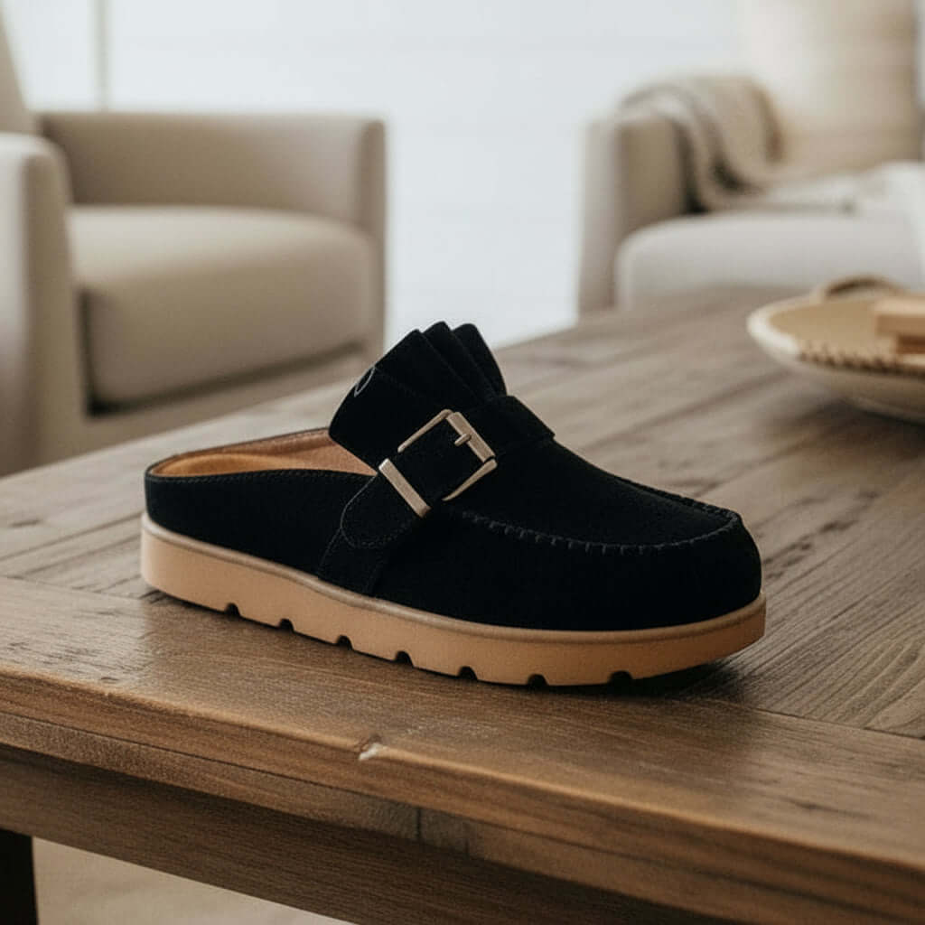 LAIDBACK LUXE SLIDES (black) featuring ruffle entrance design on a wooden table.