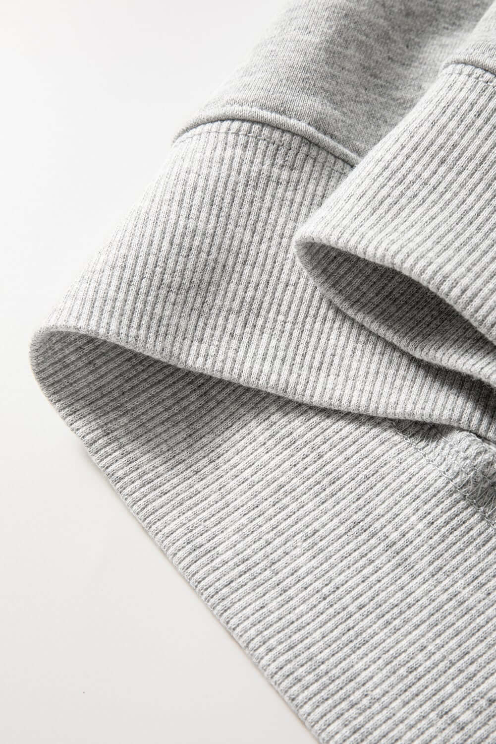 Detail of grey sweatshirt sleeve with textured fabric, showcasing a cozy and festive style for the holidays.