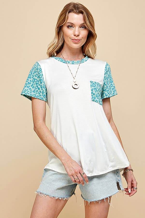Model wearing SPOT OF STYLE TEE with turquoise leopard print sleeves and pocket, styled with denim shorts.