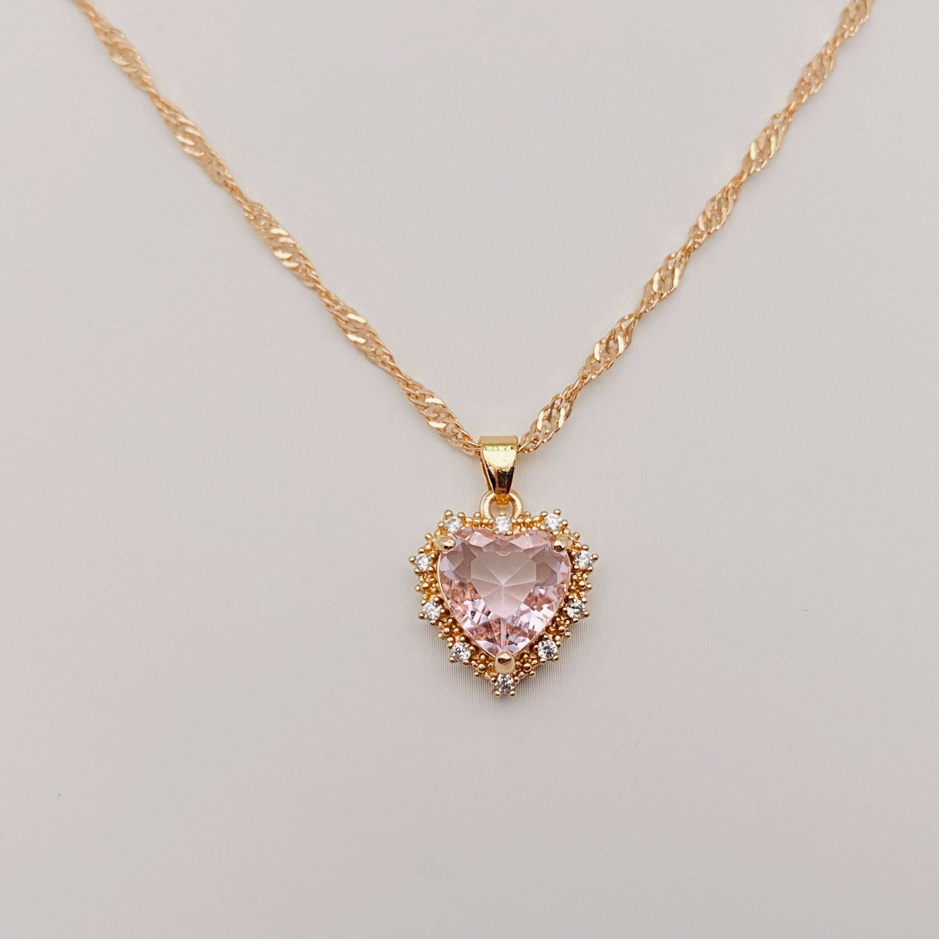 Heart-shaped Pendant Necklace Inlaid Cubic Zirconium with pink center and gold chain.
