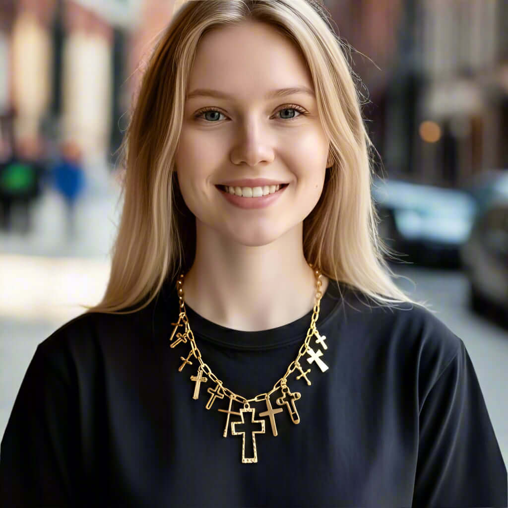 CROSS MY HEART CHARM NECKLACE worn by a smiling woman, showcasing multiple cross charms on a gold-tone chain.