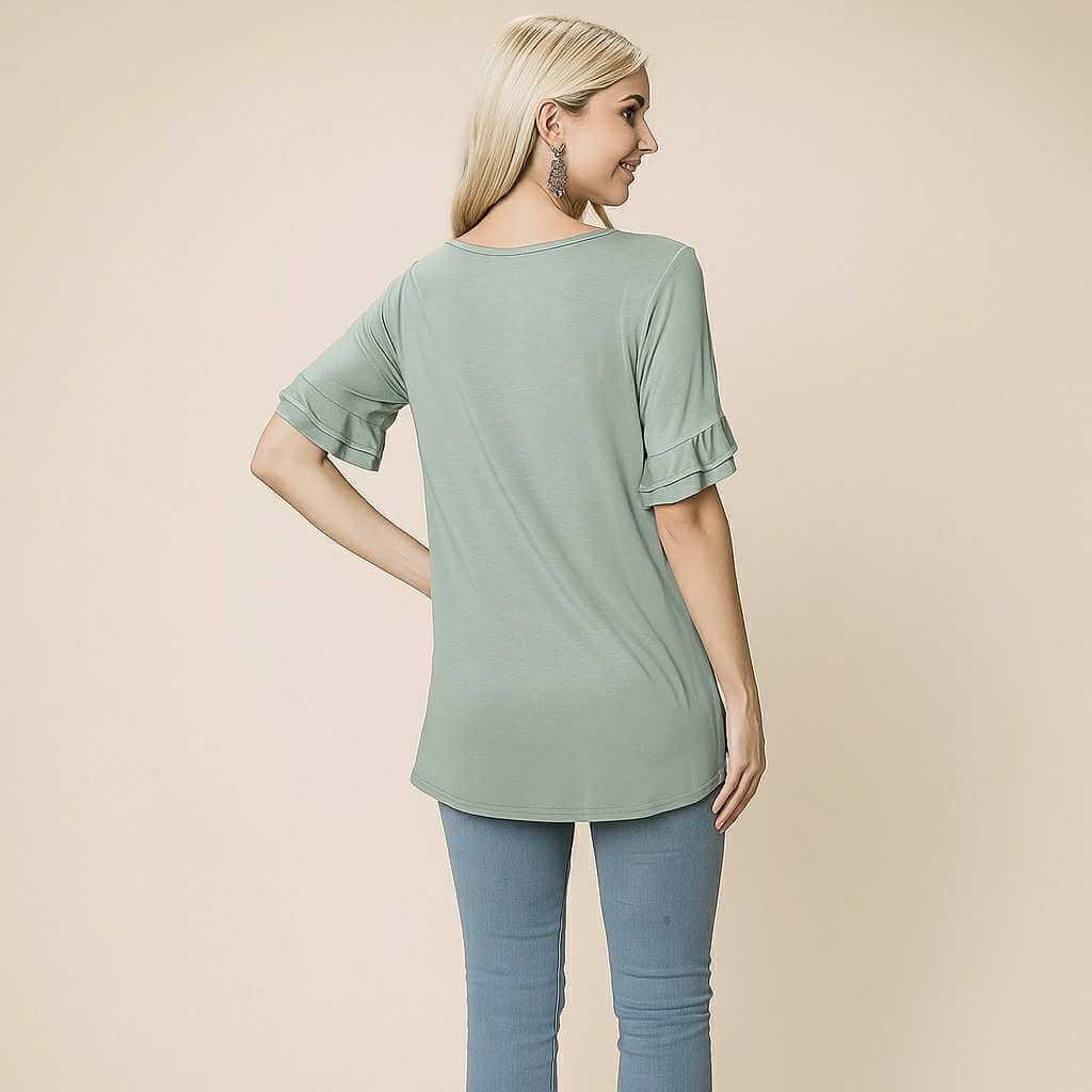 Model wearing the Delicate Directions Top in sea green, showing the back view with ruffled sleeves.
