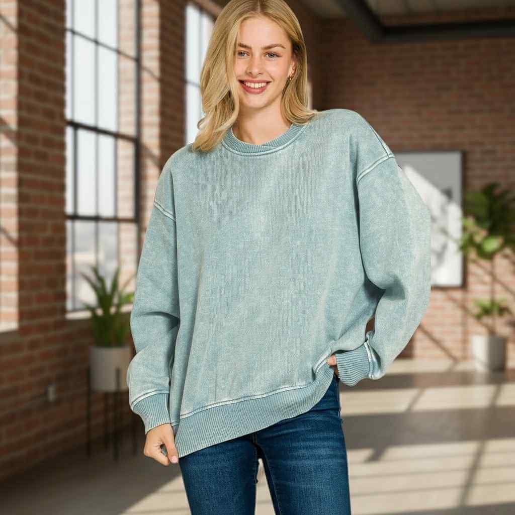Woman wearing DOWNTOWN DRIFT CREW NECK mineral wash pullover in a sunlit urban setting.