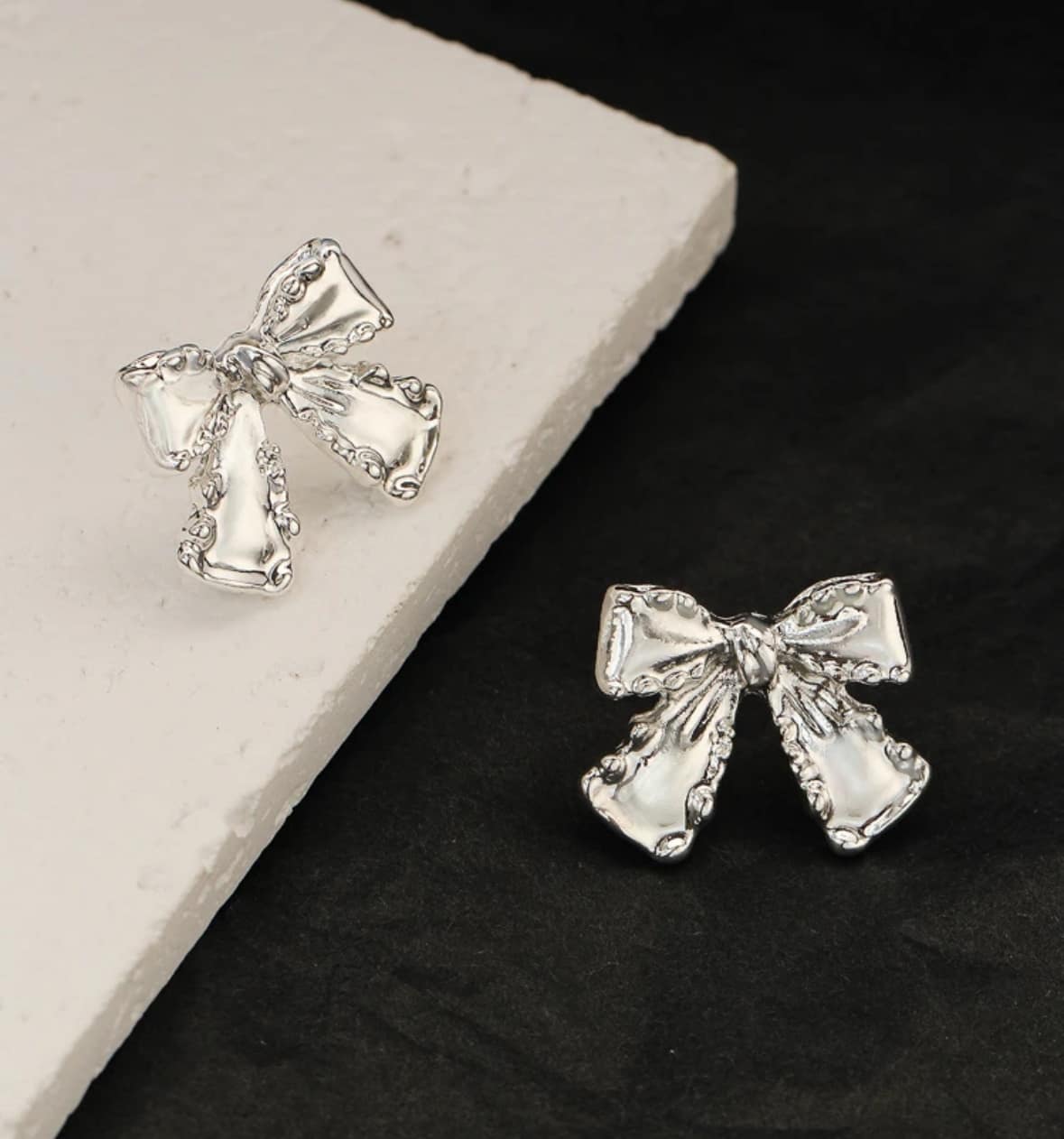 SILVER BOW Stud Earrings from Vivian-Lu collection, showcasing elegant design on a textured surface.