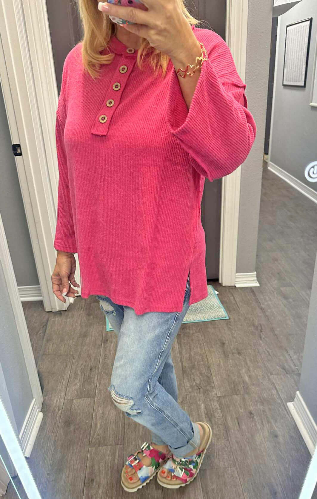 Woman wearing CASUAL CHARM TOP - Zenana in pink with side slits, styled with jeans and floral slides.