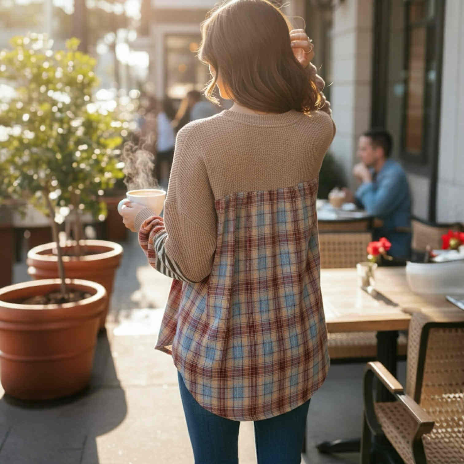 Woman wearing CAMPFIRE REMIX Top (cocoa) with plaid patchwork design, enjoying coffee outdoors.
