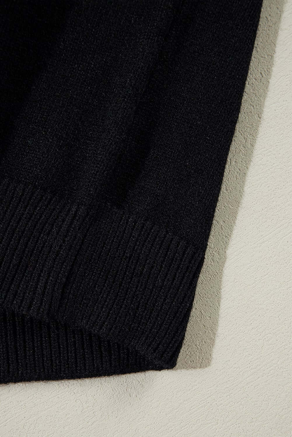 Close-up of the black MERRY & BRIGHT SWEATER by Vivian-Lu showcasing the ribbed hem detail.