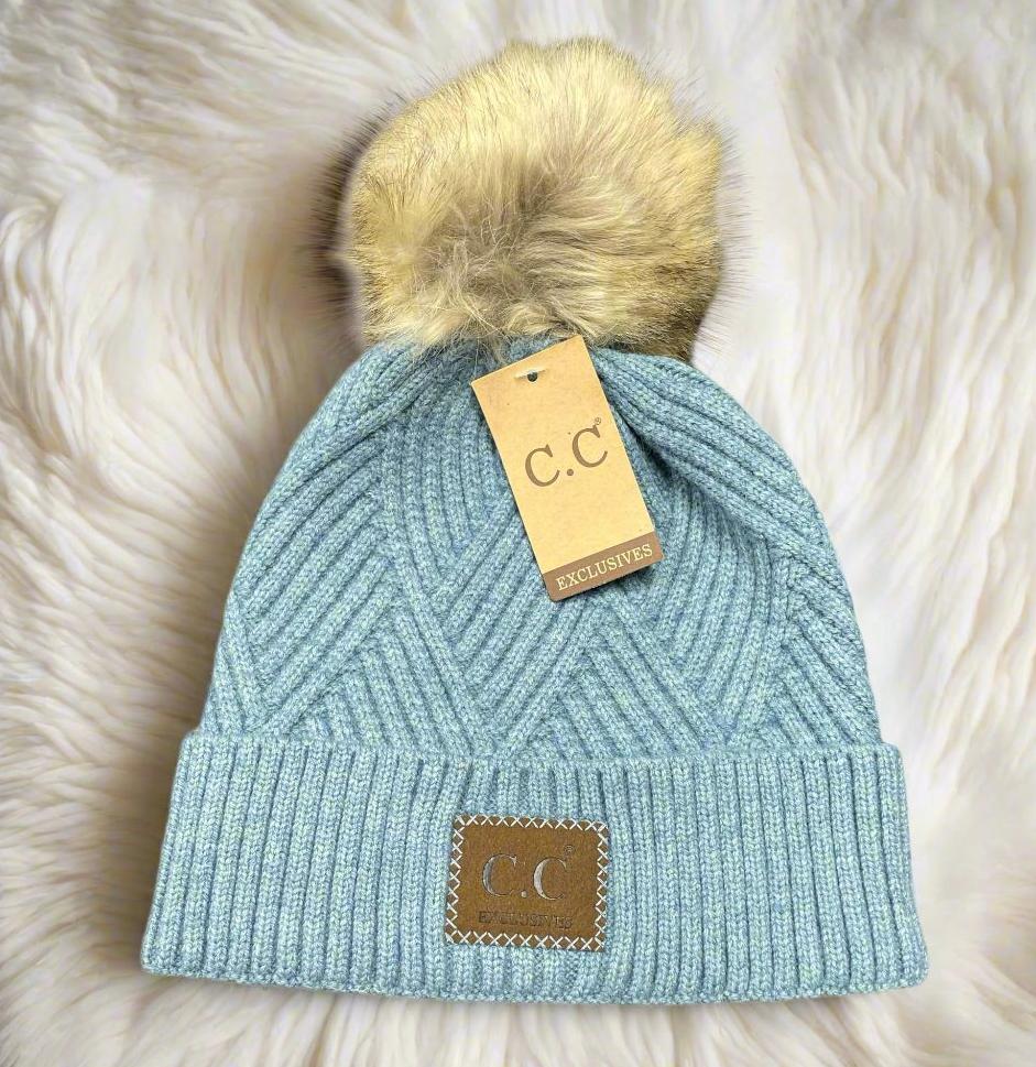Light blue warm angle beanie with faux fur pom pom, featuring a stylish diagonal pattern and C.C. tag.