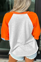 CITRUS CRUSH TOP featuring bold tangerine sleeves and light grey body, ideal for casual comfort and playful style.