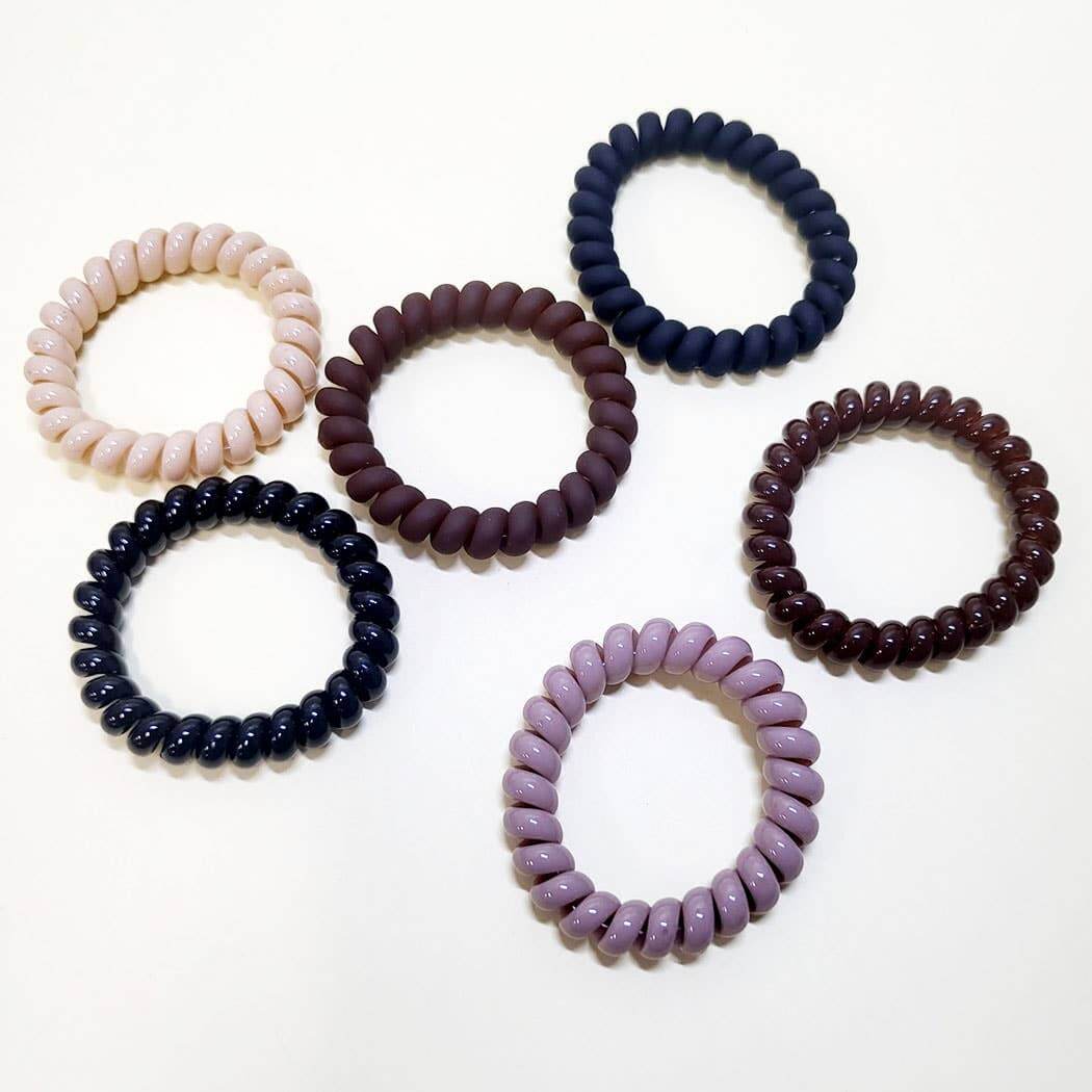 Twist & Tell Hair Tie Set featuring 6 assorted coil bands in neutral and pink tones.