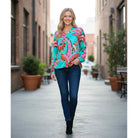 Woman modeling LAGUNA LUXE BLOUSE - JODIFL in vibrant colors with jeans in a stylish urban setting.