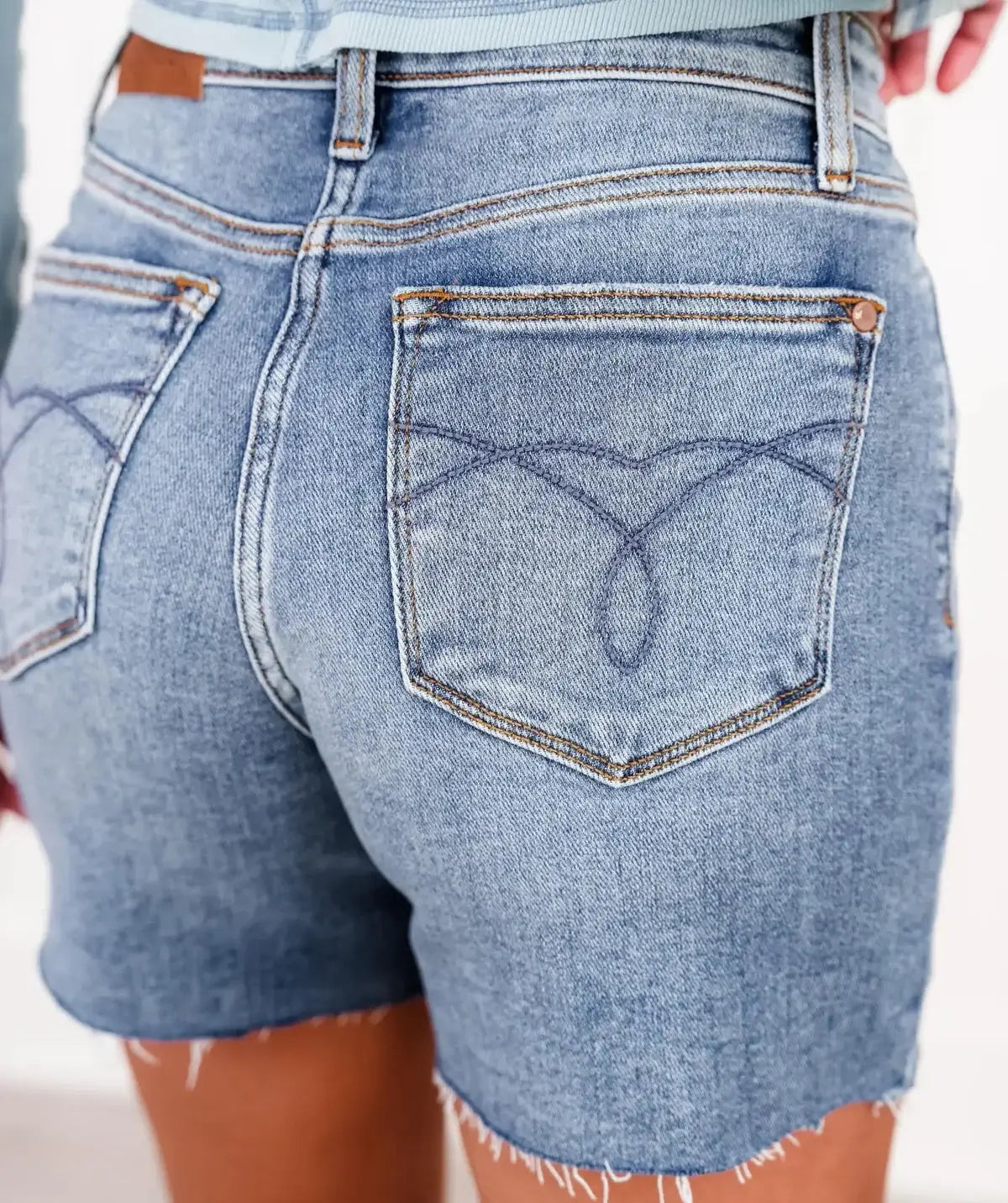 Close-up of the back pocket design on JUDY BLUE CASSIDY SHORTS, showcasing trendy denim style and frayed hem.