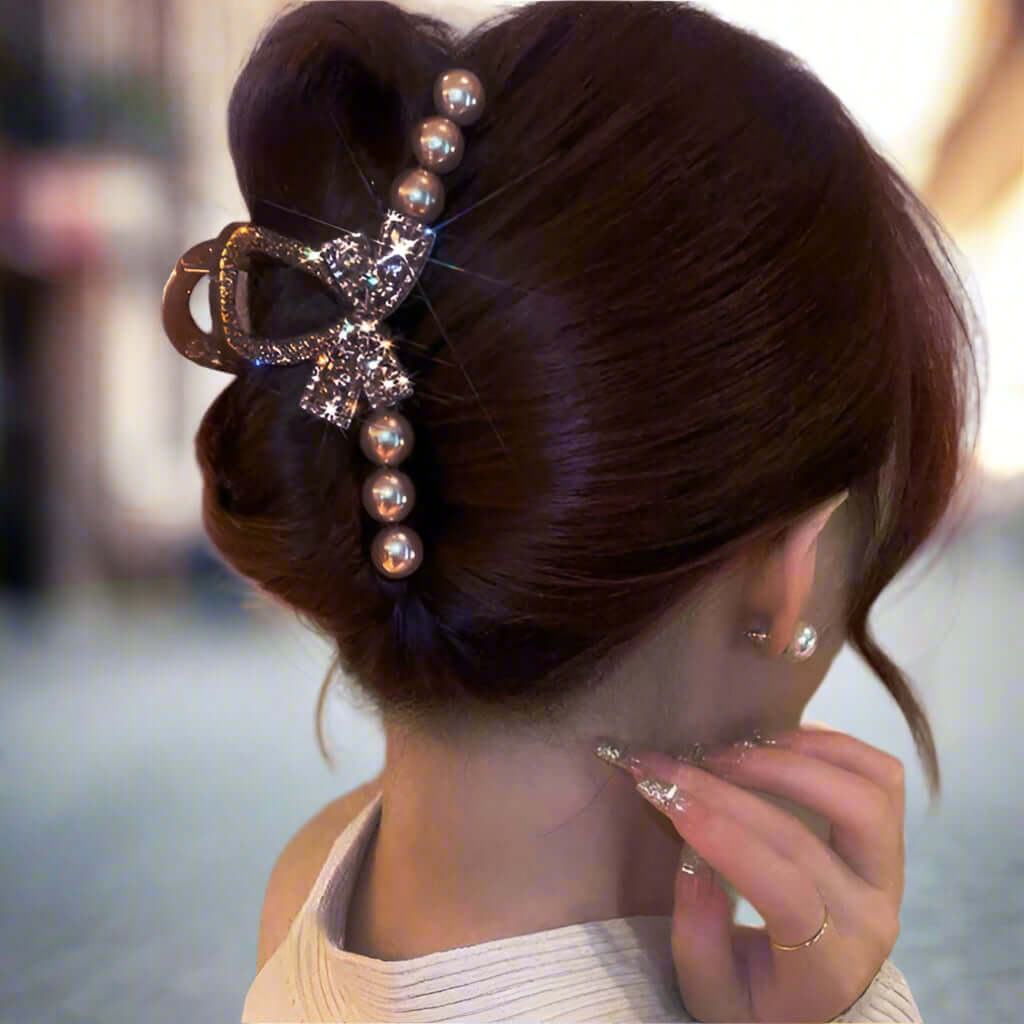 Deep rose gold Champagne Chic hair clip with rhinestone bow and pearls in an elegant updo hairstyle.