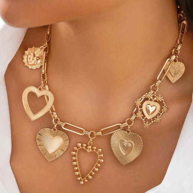 HEART TO HEART CHARM NECKLACE featuring assorted gold-tone heart pendants on a paperclip chain.