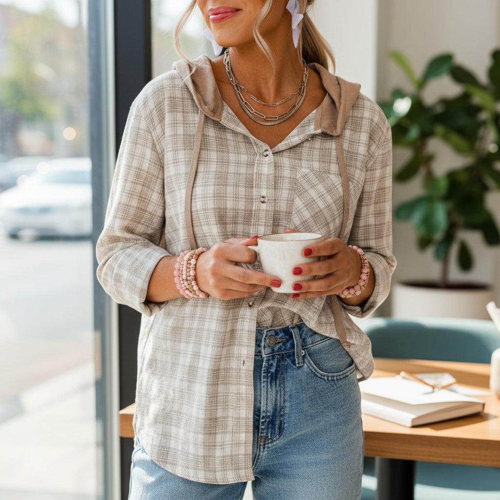 Woman wearing DRIFTWOOD DAYS BUTTON DOWN hooded shacket, holding a coffee cup in a cozy café setting.