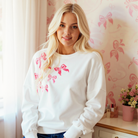 Model wearing DARLING DETAILS TOP with sequin bowknots, showcasing a high-low design and cozy style.