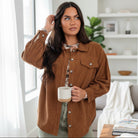 Stylish woman wearing a CINNAMON RIDGE JACKET, holding a coffee mug, in a cozy indoor setting.